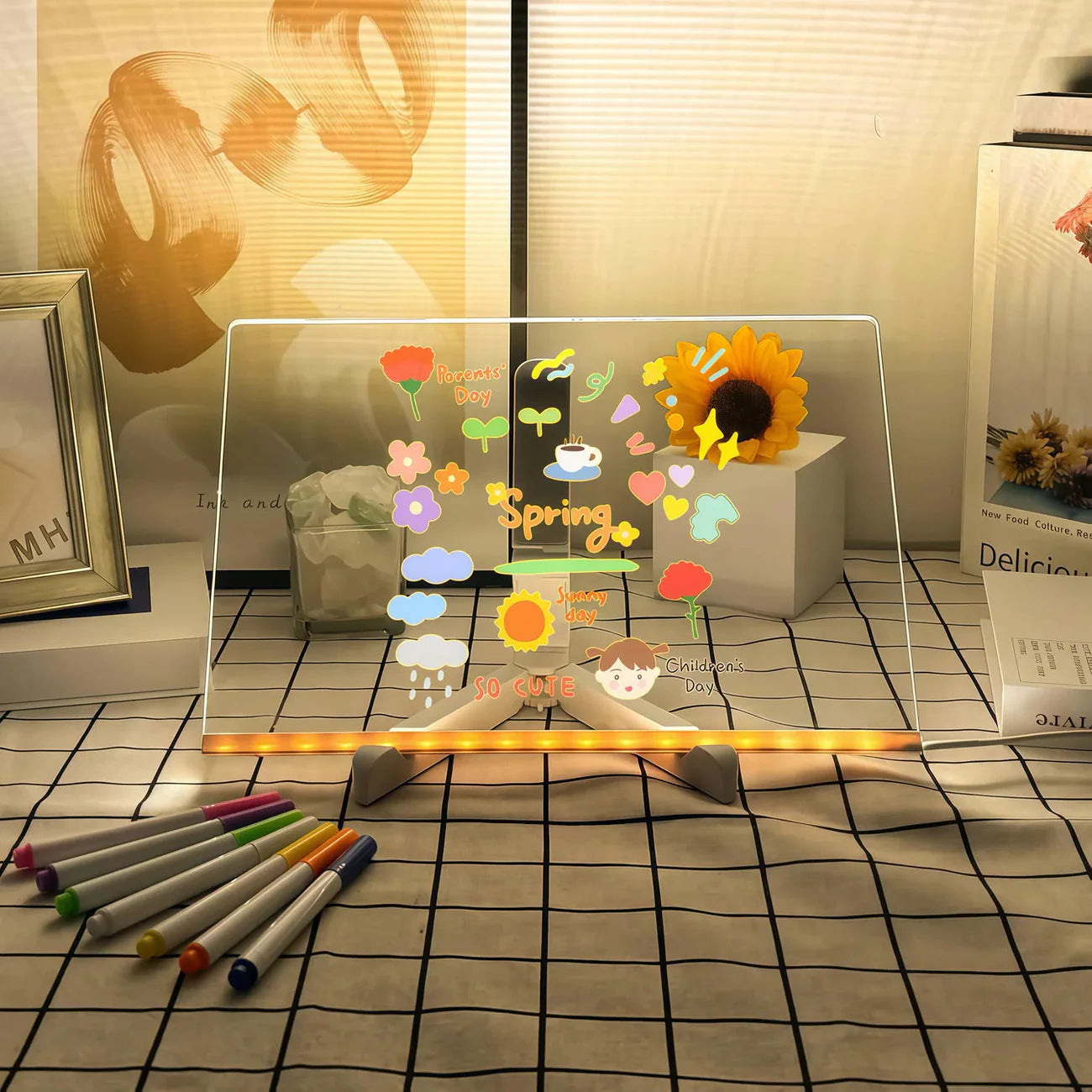 Pizarra LED LumiBoard decorada con stickers brillantes en un escritorio con luces cálidas