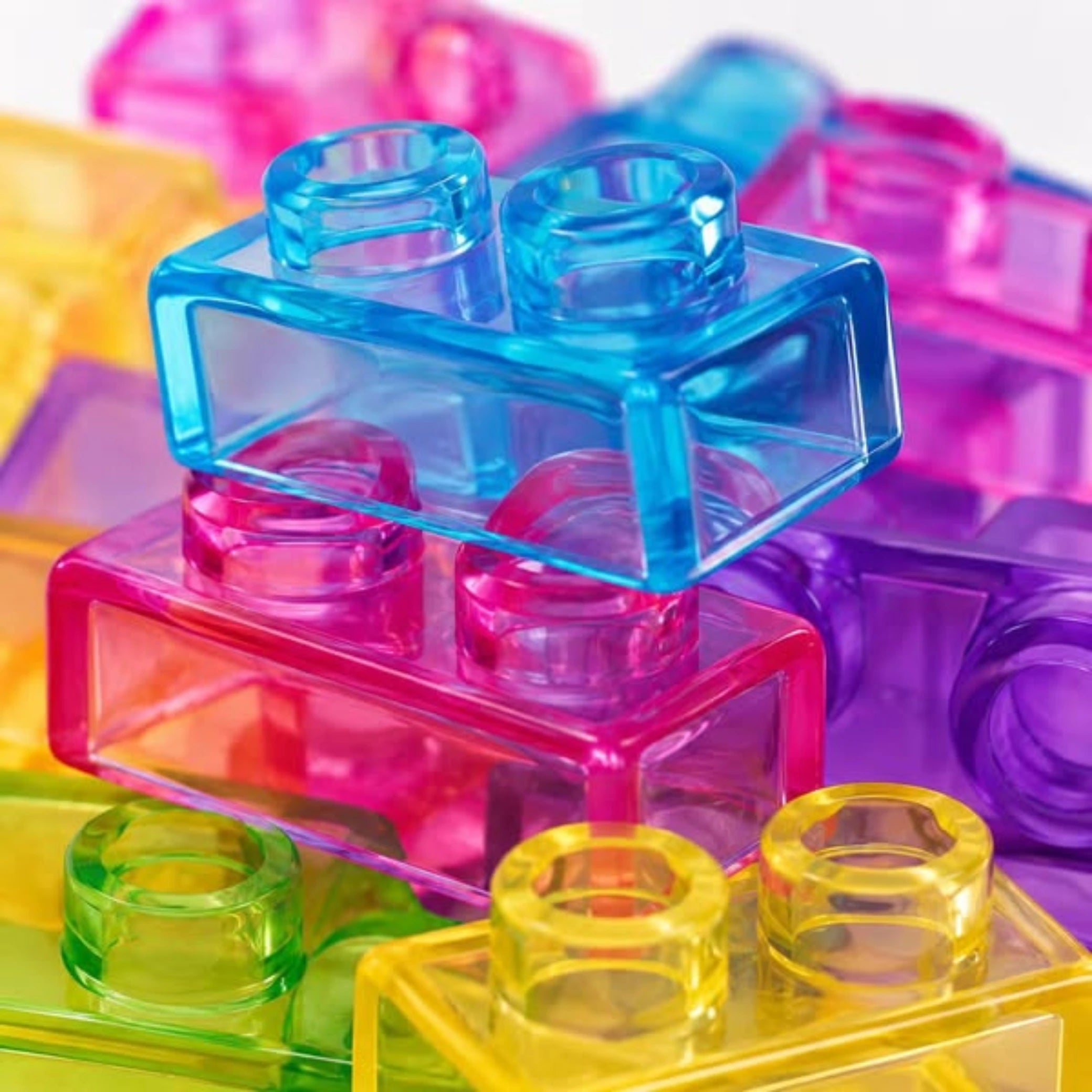 Detalle macro de los bloques translúcidos Gummy Blocks encajados por sus tetones, en colores celeste, rosa, verde y amarillo